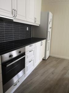 New 2 bed room apartment in Halden في هالدن: مطبخ فيه دواليب بيضاء واجهزة سوداء