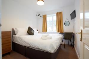 Schlafzimmer mit einem Bett mit weißer Bettwäsche und einem Schreibtisch in der Unterkunft HAVEN HOUSE DETACHED Residence in Headingley
