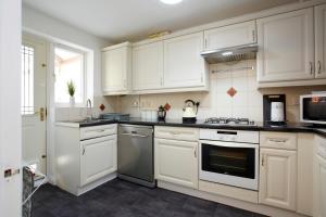 a kitchen with white cabinets and a stove top oven at HAVEN HOUSE DETACHED Residence in Headingley