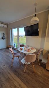 comedor con mesa, sillas y TV en Apartament Golf & Nature - Na Polu Golfowym, en Sobienie Biskupie