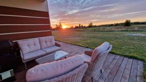 un patio con sillas, un sofá y una puesta de sol en Apartament Golf & Nature - Na Polu Golfowym, en Sobienie Biskupie