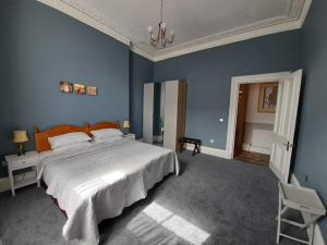 a blue bedroom with a large bed and a chair at A two bedroom apartment - Victorian Villa at 8 Priestfield Road in Edinburgh