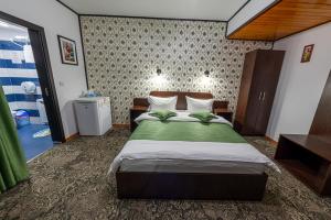 a bedroom with a large bed with a green blanket at Pensiunea Orizont in Fărcaşa