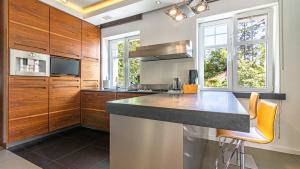 una cocina con armarios de madera y una barra con taburetes naranjas en VENTI Apartments Willa Sopot en Sopot