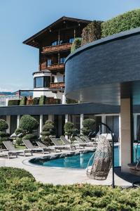 a building with a swimming pool with lounge chairs at Sonnhof Alpendorf - an adults only place in Sankt Johann im Pongau