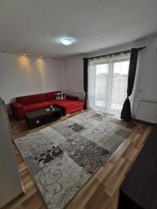a living room with a red couch and a large rug at Apartament Ovidiu in Giroc