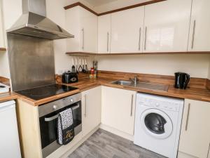a kitchen with white cabinets and a washer and dryer at The Pebbles in Hornsea
