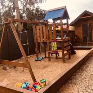 a playground with a wooden swing set in the sand at Nadmorskie Klimaty - Domki Całoroczne in Stegna