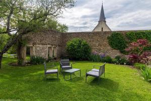 drie stoelen en een tafel in een tuin met een kerk bij Les tilleuls in Épernay-sous-Gevrey