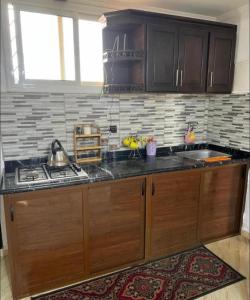 a kitchen with wooden cabinets and a stove top oven at Nice Apartement au cornich de nador in Nador