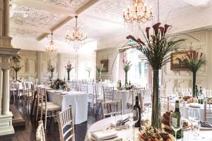 a dining room with white tables and chairs and chandeliers at HIGHFIELD in Great Driffield