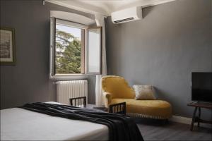 um quarto com uma cama, uma cadeira e uma janela em Le Farnete em Carmignano
