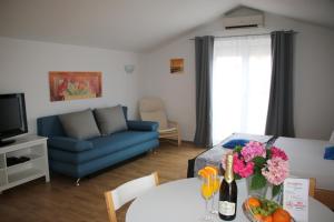 sala de estar con sofá azul y mesa con flores en Apartments Gavric, en Trogir