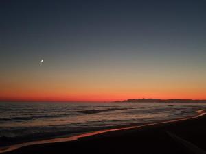 a sunset on the beach with the moon in the sky at CivicoSedici in Forte dei Marmi