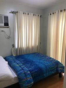 ein Bett mit blauer Decke in einem Schlafzimmer in der Unterkunft 3 Bedrooms 3 Baths Victorian style Townhouse Fully Furnished in Batangas City