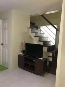 a living room with a tv and a staircase at 3 Bedrooms 3 Baths Victorian style Townhouse Fully Furnished in Batangas City