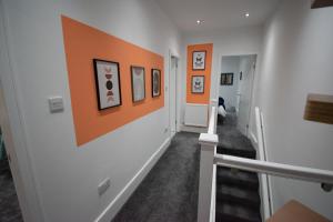 a hallway with orange and white walls and stairs at Ideal Lodgings in Accrington in Accrington