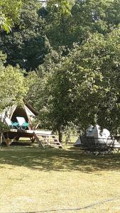 Saint-Aubin-sur-GaillonにあるLODGE EXTERIEUR 2 PERSONNES (possibilité toile de tente en plus pour efants avec futon)の木の下の椅子とテント