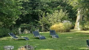 tres sillas sentadas en el césped en un patio en LODGE EXTERIEUR 2 PERSONNES (possibilité toile de tente en plus pour efants avec futon), en Saint-Aubin-sur-Gaillon