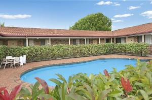 a swimming pool in front of a house at Ballina Travellers Lodge in Ballina