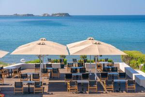 een restaurant met tafels en stoelen en parasols op het strand bij Costa Rossa Boutique Hotel - Adults Only in Lixouri