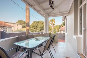 a patio with a table and chairs on a balcony at Hampton Collection - Charming 1 or 2 Bedroom Apartment with Pool in Durban
