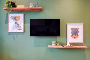 a flat screen tv on a green wall with two pictures at Hampton Collection - Charming 1 or 2 Bedroom Apartment with Pool in Durban