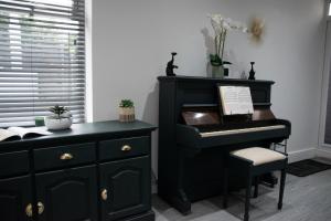 a black piano in a room with a chair at Ideal Lodgings in Accrington in Accrington