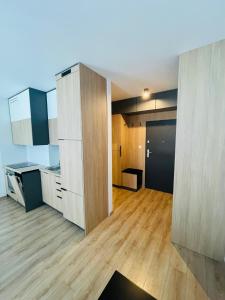 Apartament Osiedle Okrzei في كيلسي: مطبخ كبير مع أرضيات خشبية ودواليب بيضاء