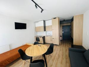 eine Küche und ein Wohnzimmer mit einem Holztisch und Stühlen in der Unterkunft Apartament Osiedle Okrzei in Kielce