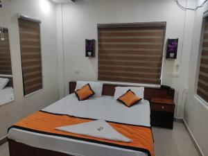 a small bedroom with a bed with orange pillows at PMS Dhabi Residency in Kottakkal