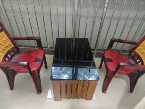 two red chairs with a table in between them at PMS Dhabi Residency in Kottakkal