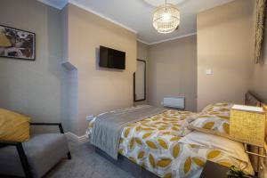 a bedroom with a bed and a chair and a tv at Coral Boutique Apartment 2 in Blackpool