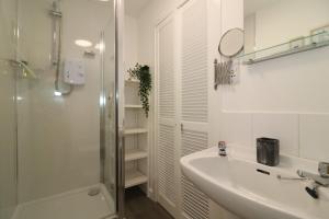 a white bathroom with a sink and a shower at Signature - Barons Court in Paisley