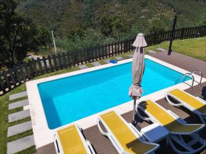 una piscina con tumbonas, una sombrilla y una piscina en Quinta da Resteva-Chalé do RIBEIRO en Vieira do Minho