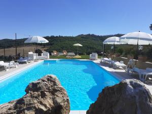basen z błękitną wodą, skałami i parasolami w obiekcie Casale Il Ventaglio w mieście Ficulle