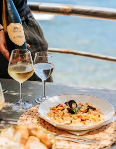 einen Tisch mit einem Teller Essen und zwei Gläsern Wein in der Unterkunft O' Vagnitiello - Parco Balneare Idroterapico - Camere - Ristorante in Ischia
