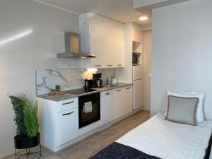 a kitchen with white cabinets and a couch in a room at Hotel Aakenus Apartment Korkalo in Rovaniemi