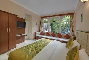 1 dormitorio con 1 cama, TV y ventanas en Hotel Raj Palace by Howard, en Udaipur
