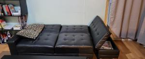 a black leather couch in a living room at Double room in a cosy flat in Tooting in London