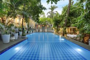 a swimming pool with palm trees and a resort at Hotel Raj Palace by Howard in Udaipur