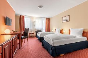 a hotel room with two beds and a desk at AZIMUT Hotel Nuremberg in Nuremberg