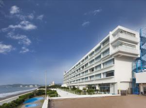 ein weißes Gebäude mit dem Ozean im Hintergrund in der Unterkunft Kamogawa Sea World Hotel in Kamogawa