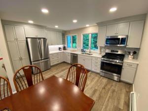 a kitchen with white cabinets and a wooden table with a dining room at R7 Ski-in Ski-out Bretton Woods Townhome on 2-mile home trail Mt Washington views in Carroll