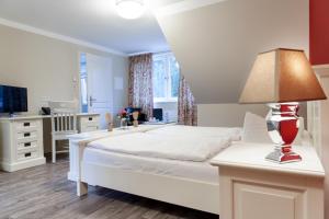 ein Schlafzimmer mit einem weißen Bett und einem Tisch mit einer Lampe in der Unterkunft Pension am Werbellinkanal in Eichhorst