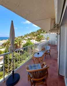 a balcony with chairs and tables and the ocean at Siesta Mar Apartamentos Ibiza in Santa Eularia des Riu