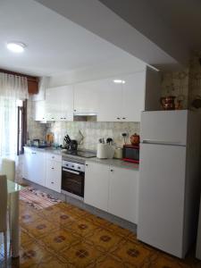 a kitchen with white cabinets and a white refrigerator at Piso en centro urbano de Puentedeume con terraza in Puentedeume