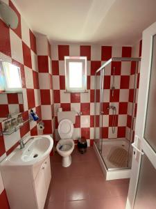 a red and white bathroom with a toilet and a sink at Casa RBK in Vama Veche