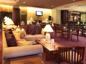 a living room with a couch and tables and chairs at Grand Zuri Dumai in Dumai