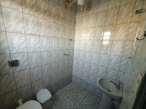 a tiled bathroom with a toilet and a sink at Hotel Jin Ju in Arujá
